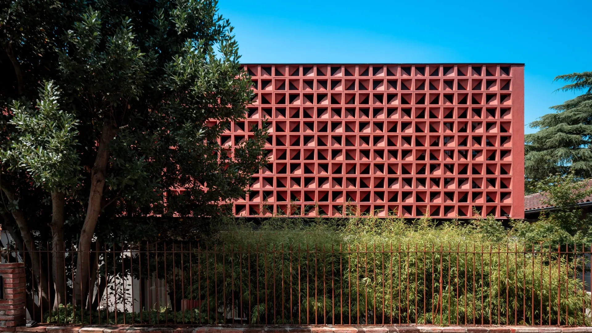 Une clôture de bambous préserve d’une vue plongeante sur le rez-de-chaussée semi-enterré, contribuant à l’effet de légèreté de la façade du premier étage.