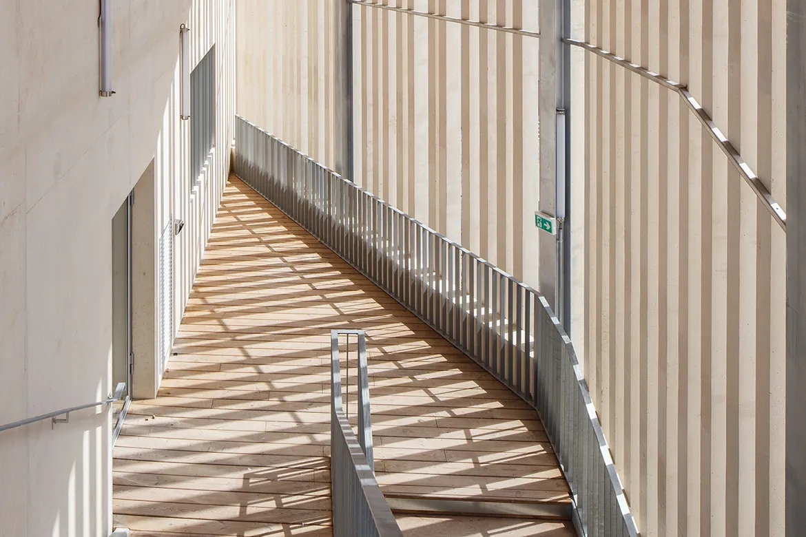 Les lames béton des claustras, réalisées en préfabrication foraine, permettent de créer une enveloppe continue qui intègre les espaces de circulation à la volumétrie générale. Les lames béton des claustras, réalisées en préfabrication foraine, permettent de créer une enveloppe continue qui intègre les espaces de circulation à la volumétrie générale.