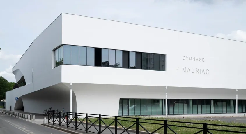 Gymnase François-Mauriac – Le gymnase semble découpé dans son épaisseur pour générer des auvents protecteurs et apporter de la lumière naturelle dans chacune des salles.