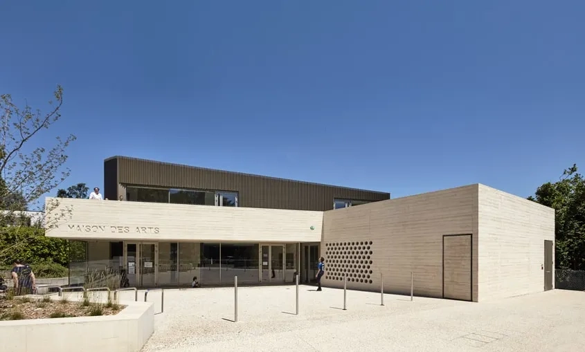 Signifiée par un large porte-à-faux en béton et face au parvis, l’entrée de la maison des arts est en façade sud du bâtiment, au niveau du rez-de-chaussée.