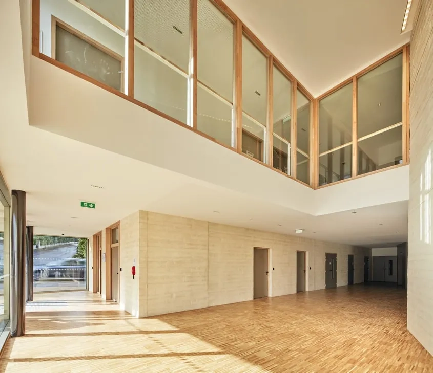 Le hall d’entrée généreux et lumineux offre des vues sur le premier étage par une dilatation verticale de l’espace. Sa forme en entonnoir accompagne les visiteurs vers le cœur du projet.