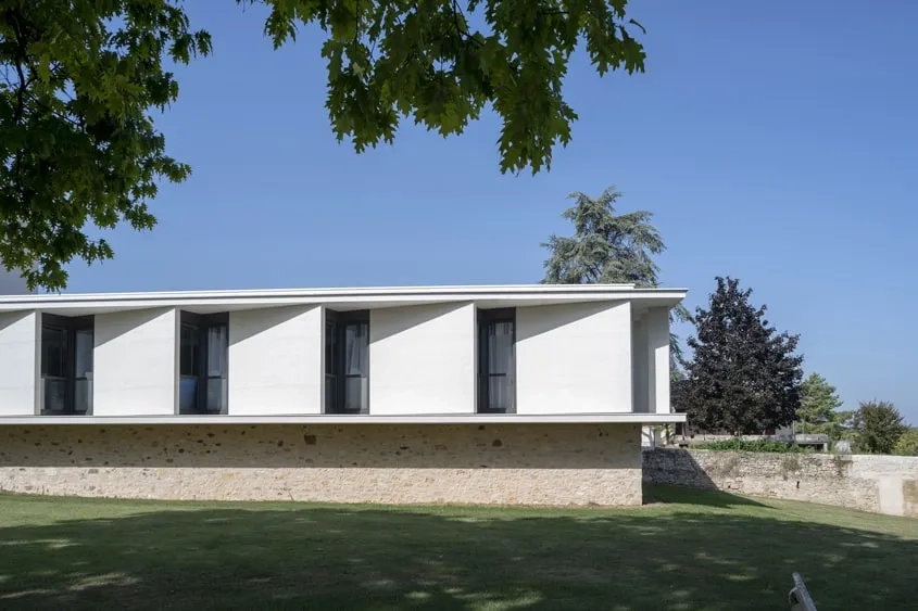 Le décalage diagonal du mur en béton blanc matricé de chaque chambre crée un jeu de redents successifs.