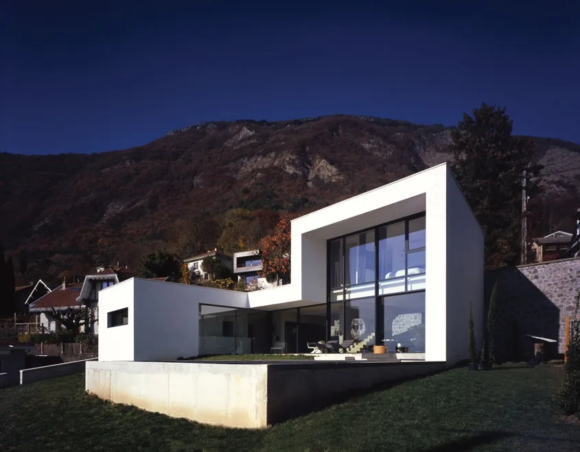Le volume de la maison est façonné par un enchaînement continu de parois verticales et horizontales en béton recouvertes d’un enduit blanc.