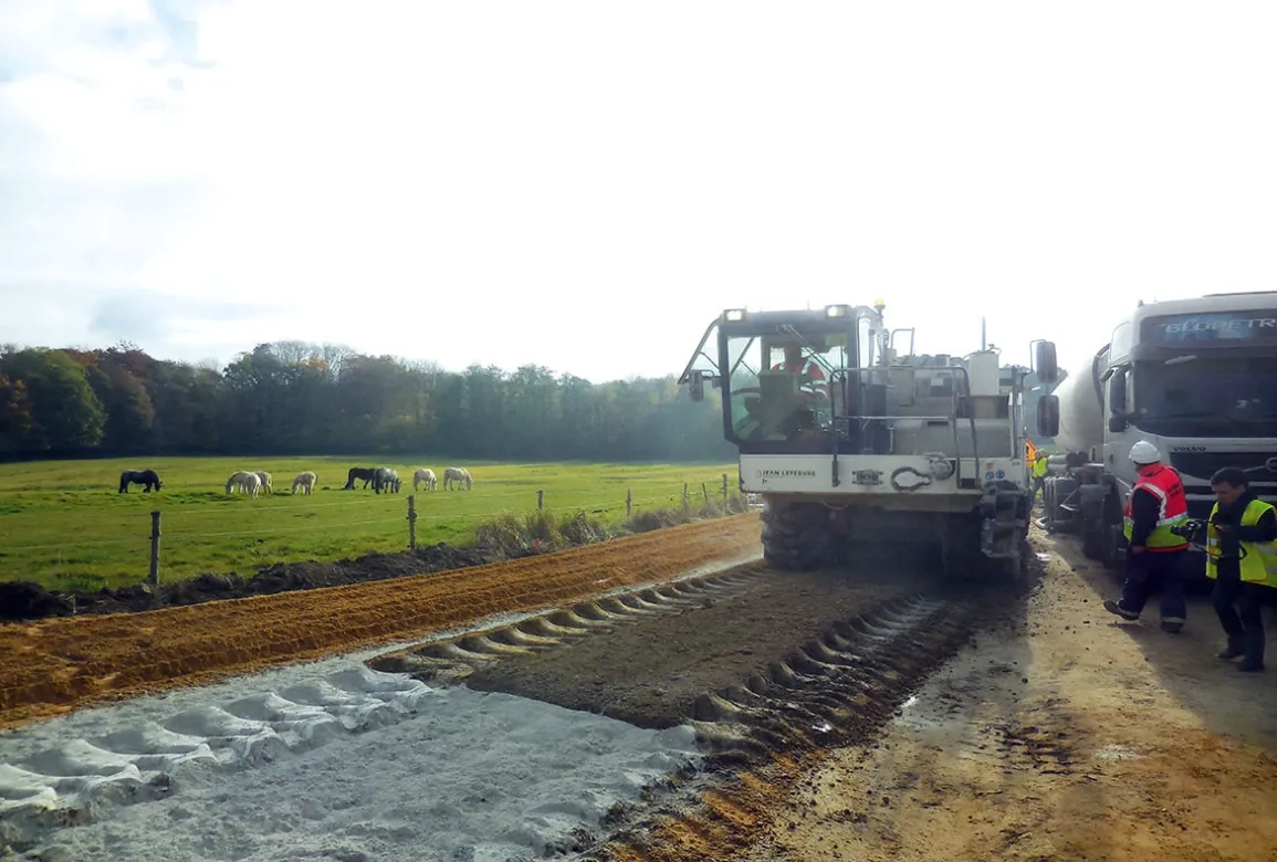 Travaux en cours sur la RD48. Au premier plan : le liant épandu (de couleur claire) avant malaxage par la Wirtgen WR-400 d’Eurovia.